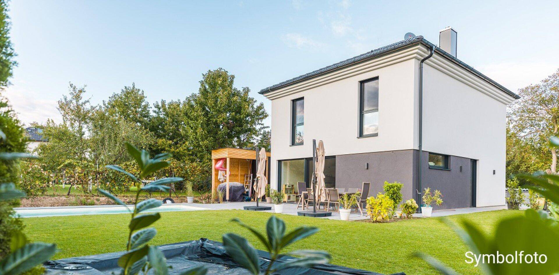 Gepflegter Garten mit Rasenfläche, Gartenhaus und Terrasse am modernen Einfamilienhaus.