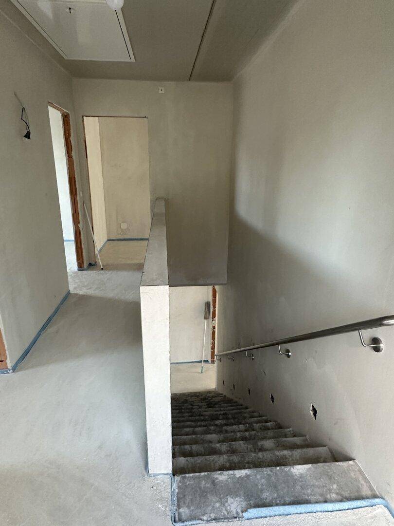 Rohbau-Treppenhaus mit Betonstufen und Geländer, das die Stockwerke verbindet.