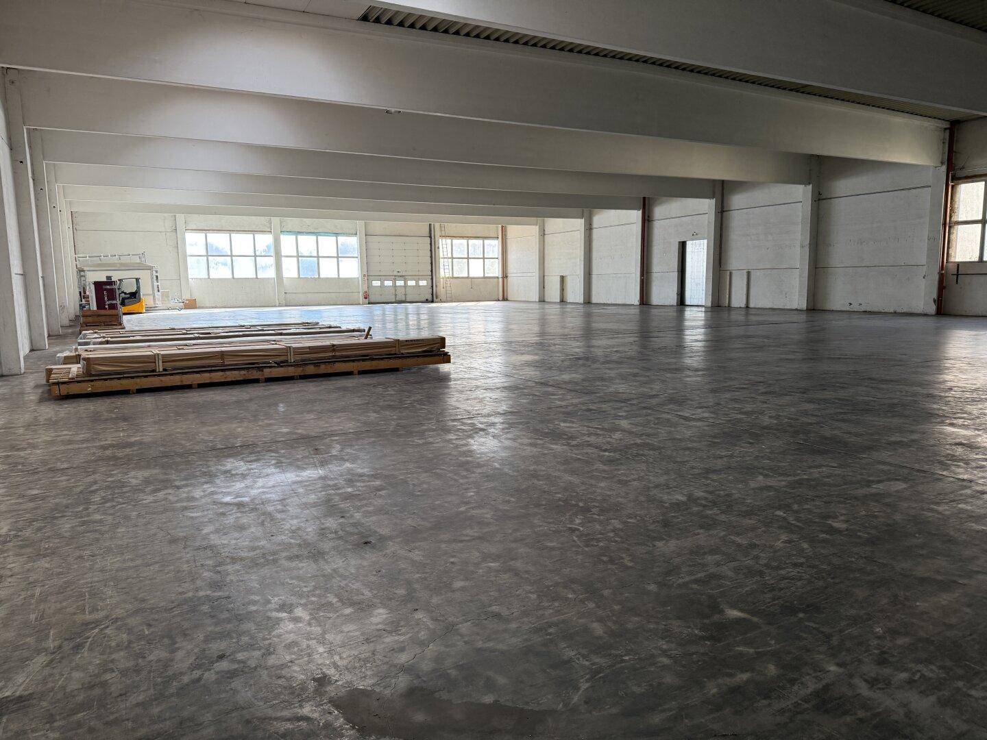 Weitläufige Industriehalle mit robustem Betonboden und hohen Decken, ideal für Lagerung oder Produktion.