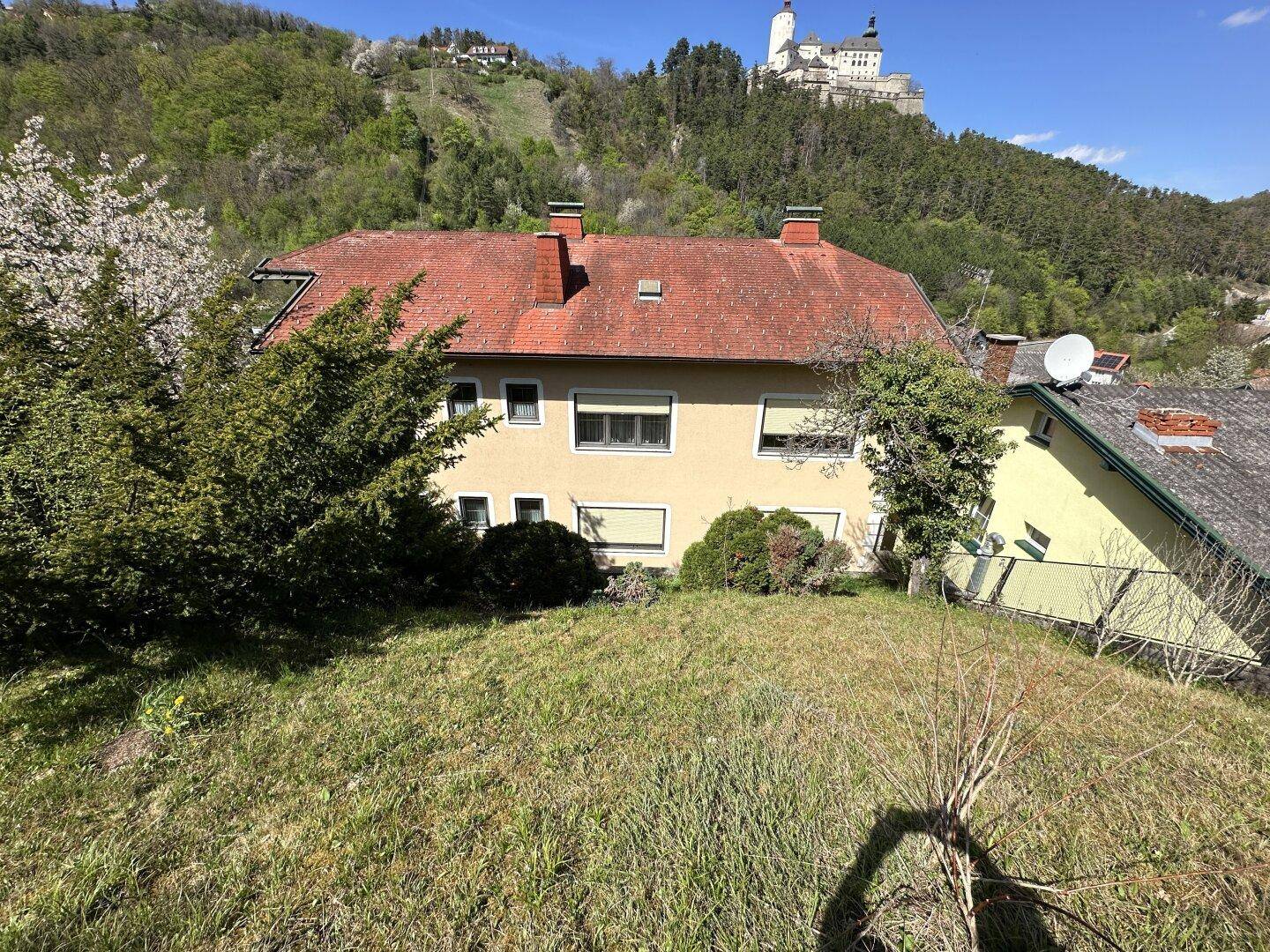 Hinteransicht des Hauses mit Gartenbereich und Blick auf eine Burg auf dem Hügel.