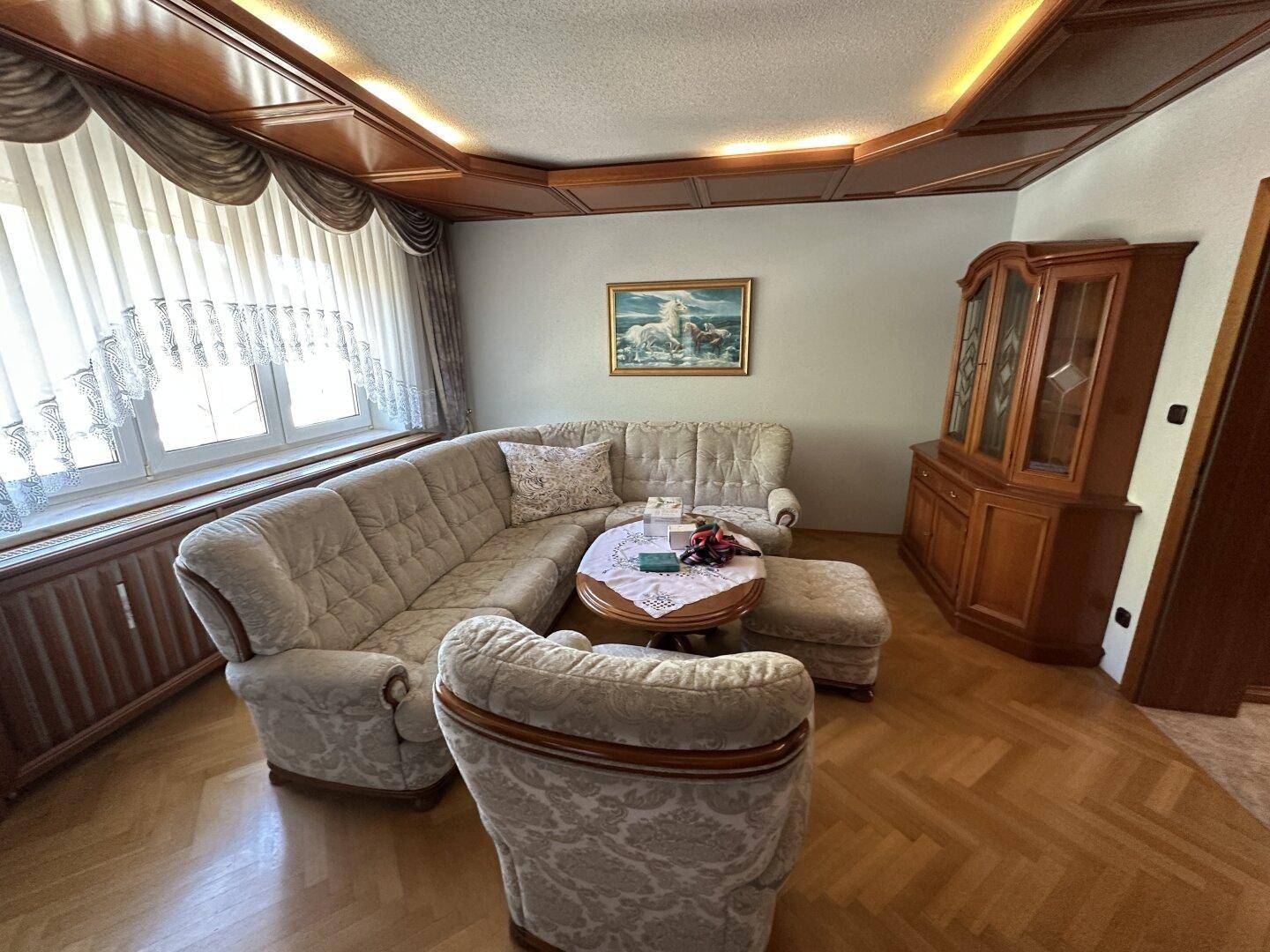 Helles Wohnzimmer mit bequemer Sofagarnitur, Holzdecke und Fischgrätparkettboden.