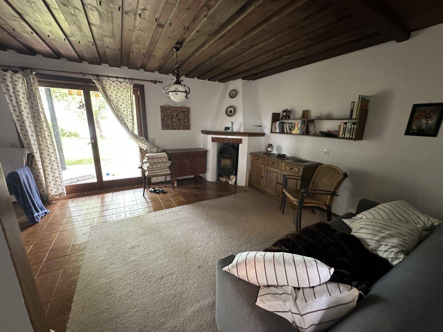 Helles Wohnzimmer mit Kamin, Teppichboden und direktem Zugang zur Terrasse.