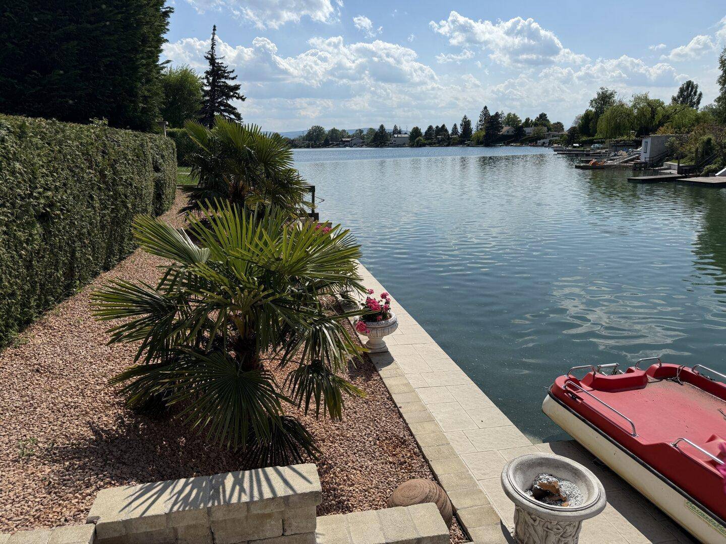 Malerischer Seeblick vom Ufer des Anwesens mit Palmen und einem kleinen Boot.