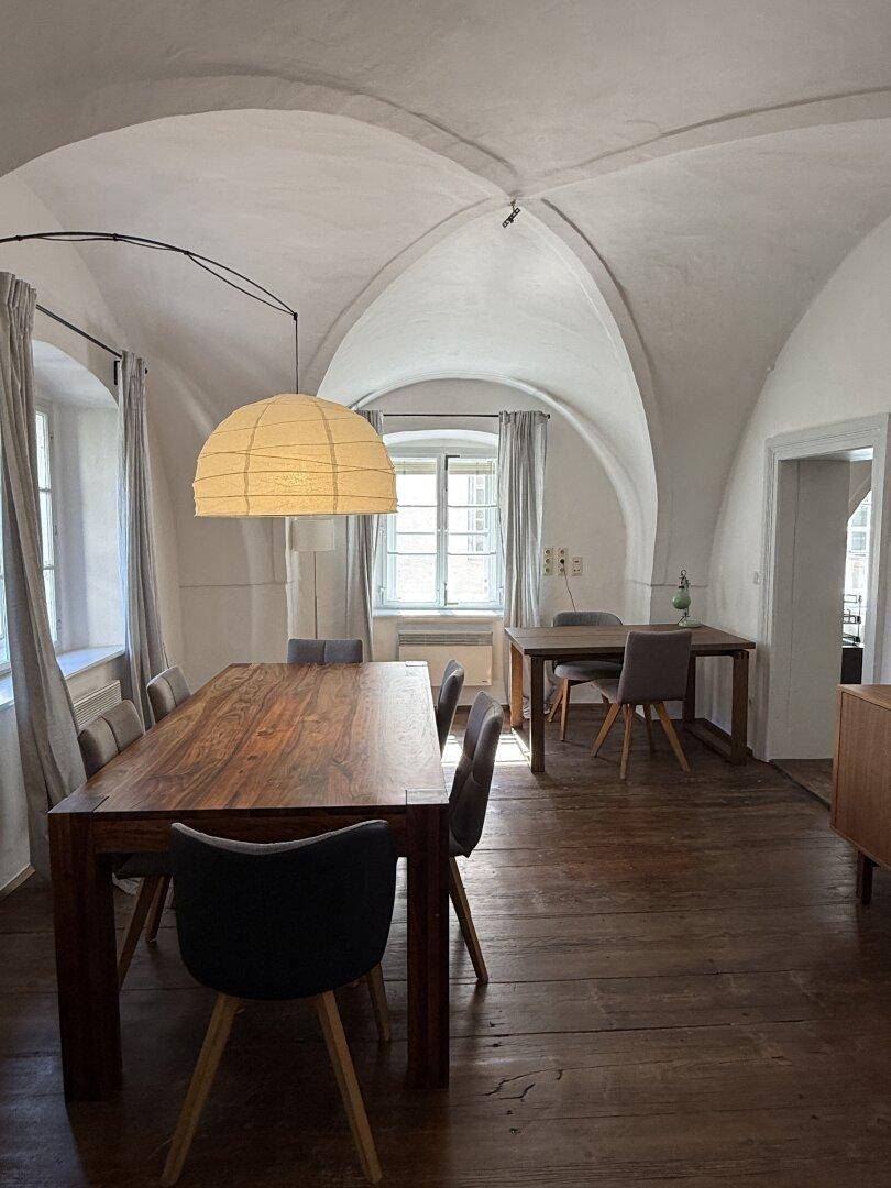 Stilvoller Essbereich mit Gewölbedecke, Holzdielenboden und einem großen Holztisch.