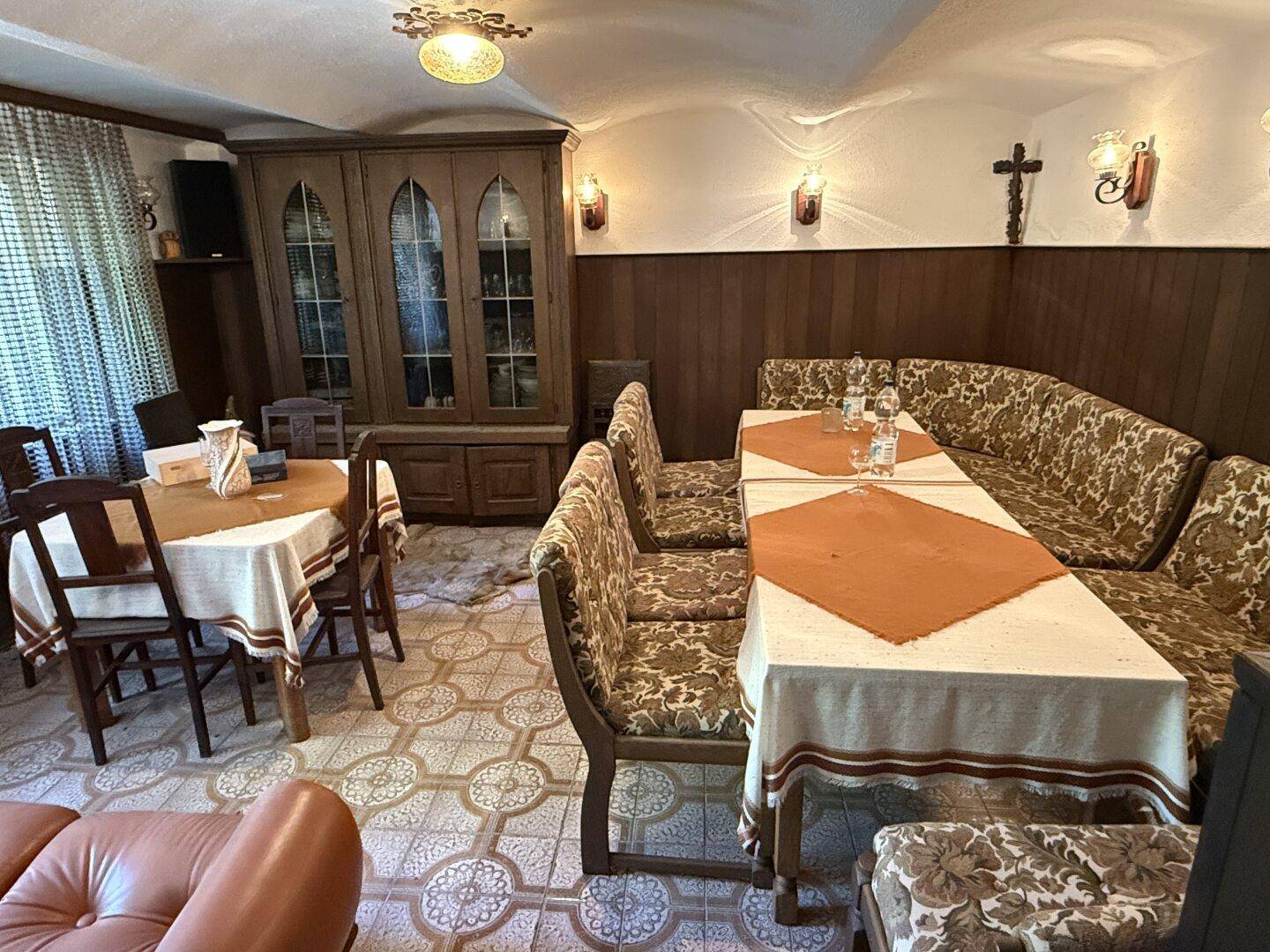 Rustikaler Partyraum im Keller mit Holztäfelung, Sitzbänken und traditioneller Dekoration.