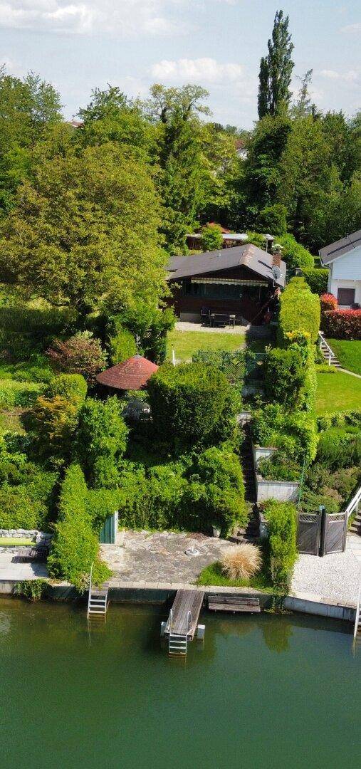 Luftaufnahme eines Hauses mit großem Garten und direktem Seezugang.