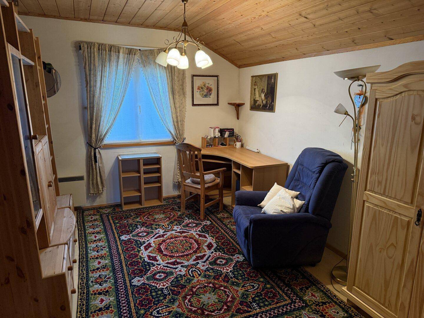 Gemütliches Arbeitszimmer mit Holzdecke, Teppichboden und traditionellen Holzmöbeln.