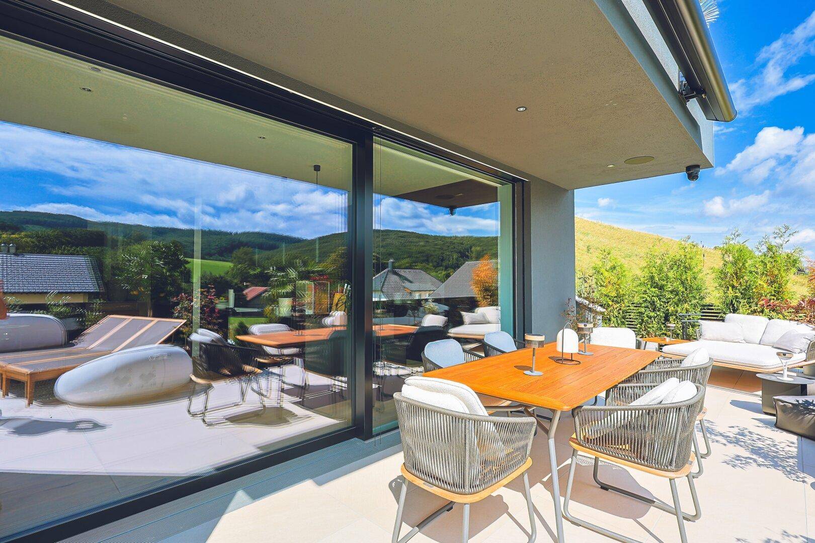 Geräumige Terrasse mit Esstisch, Lounge-Möbeln und Panoramablick auf die Hügellandschaft.