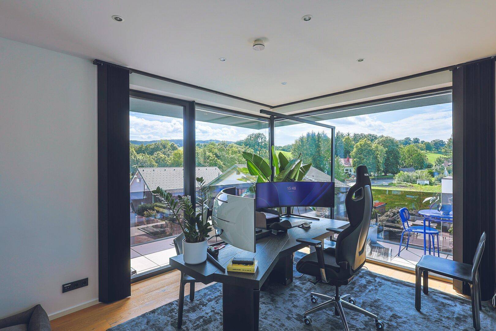 Helles Arbeitszimmer mit großen Fenstern und weitem Blick auf die grüne Landschaft.