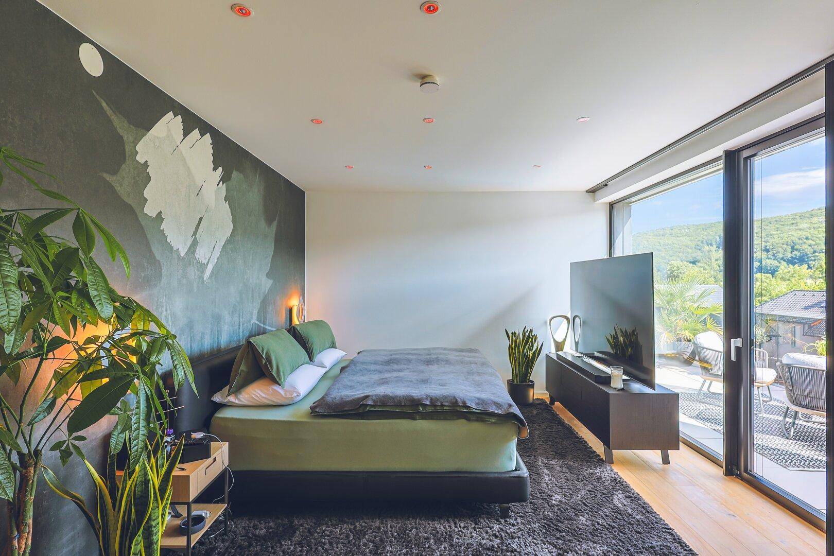 Modernes Schlafzimmer mit großem Bett, Kunst an der Wand und Terrassenzugang.