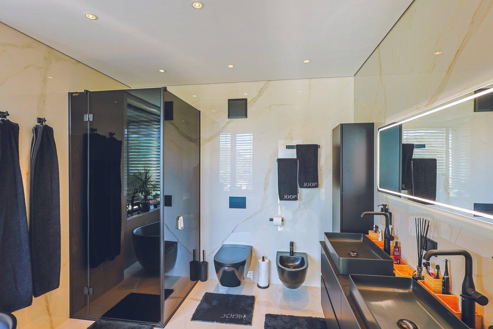 Elegantes Badezimmer mit schwarzen Armaturen, Doppelwaschbecken und begehbarer Dusche.