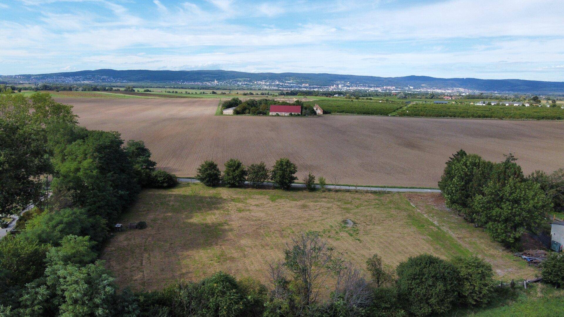 Luftaufnahme eines großen Grundstücks mit Ackerland und einer Stadt am Horizont.