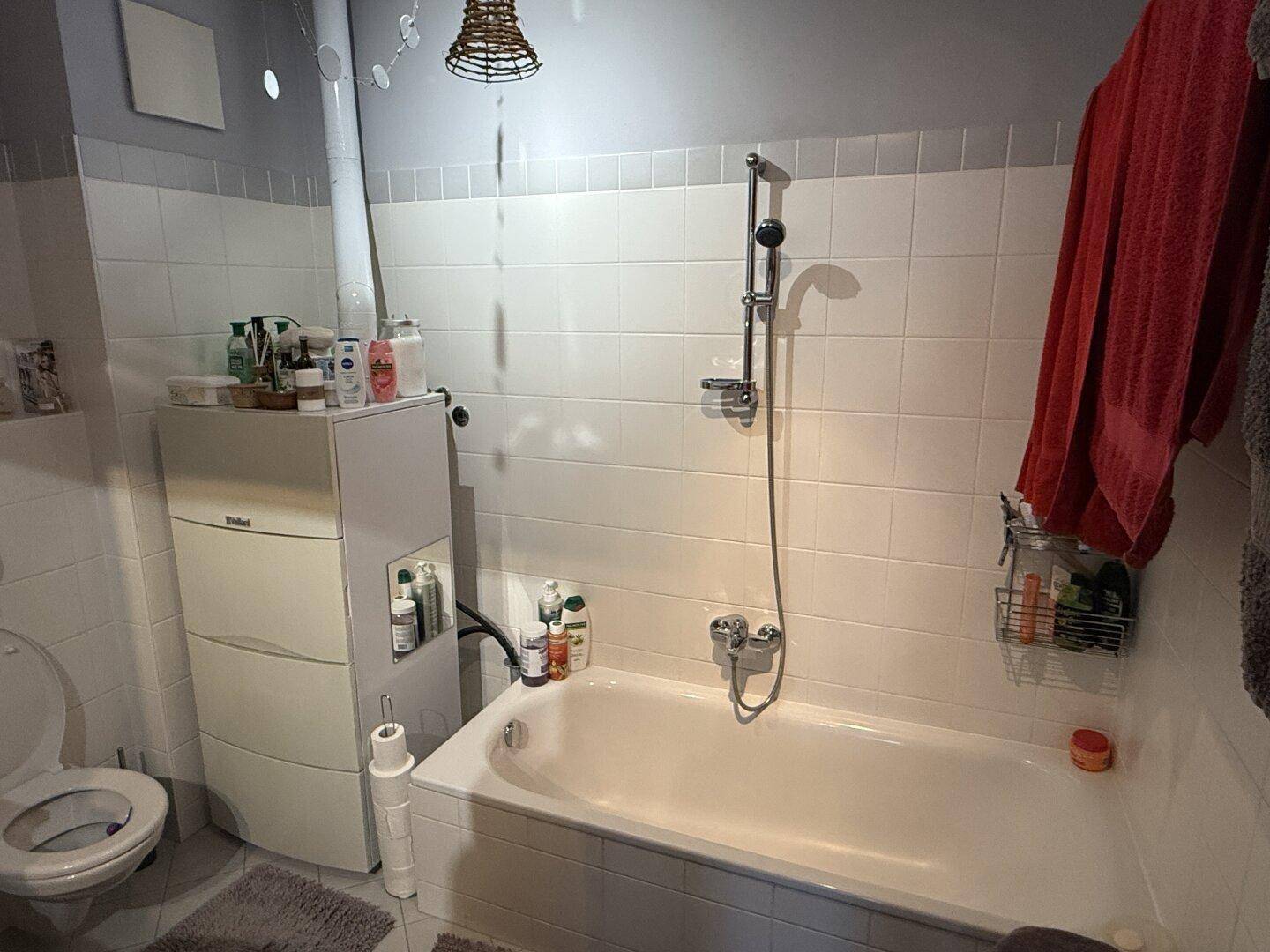Badezimmer mit Badewanne, Duschfunktion und weißen Fliesen, funktional eingerichtet.