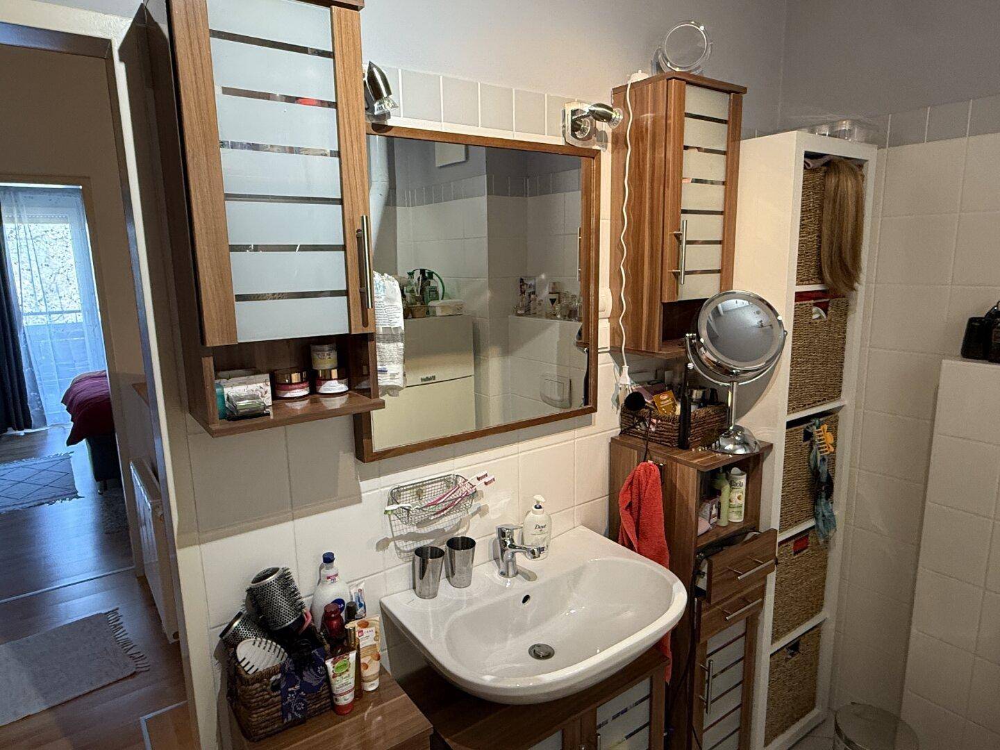 Badezimmer mit Einzelwaschbecken, Spiegelschrank und Holzmöbeln, praktisch gestaltet.