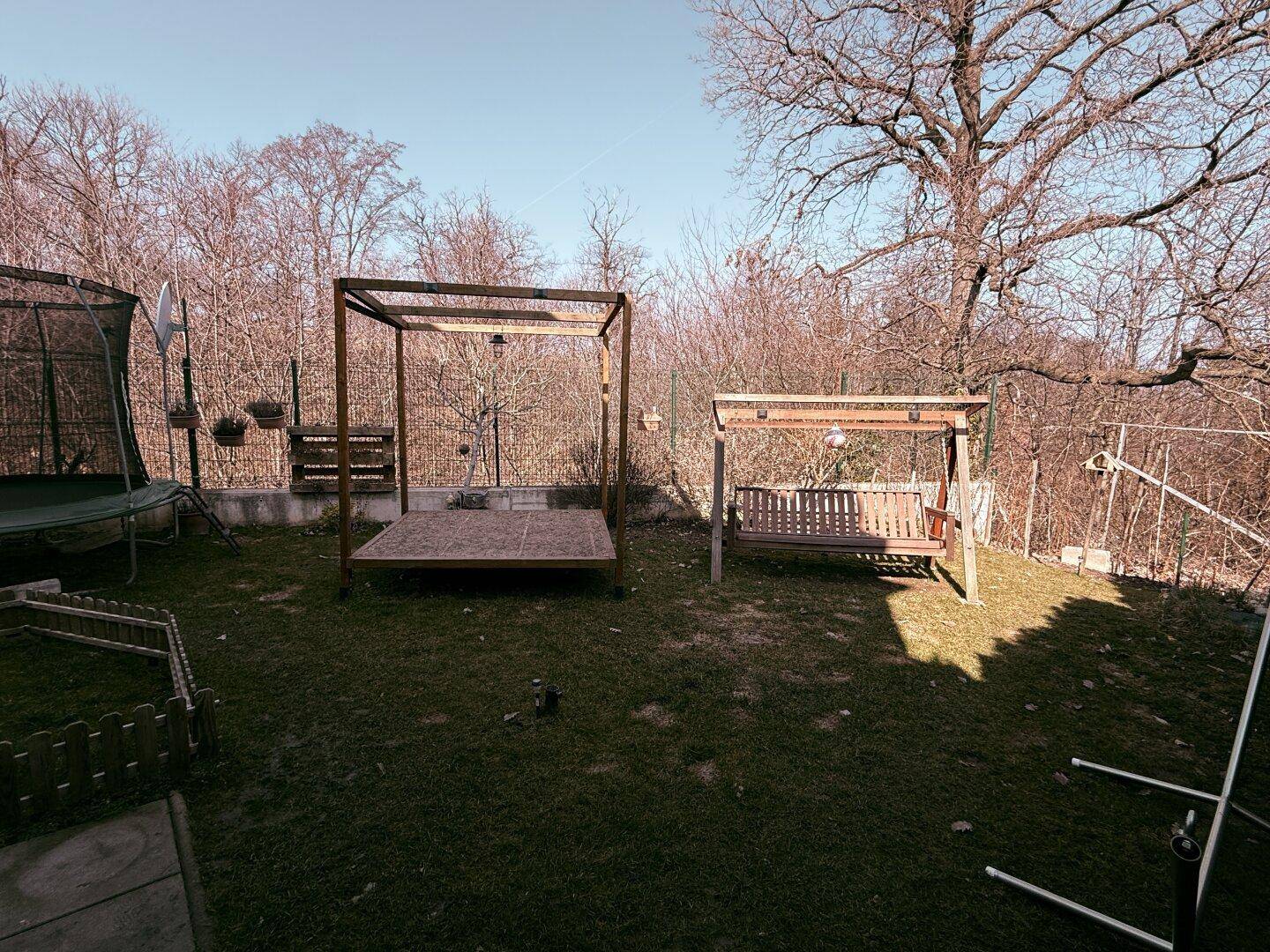 Großer Gartenbereich mit Schaukel, Trampolin und viel Platz für Freizeitaktivitäten im Freien.