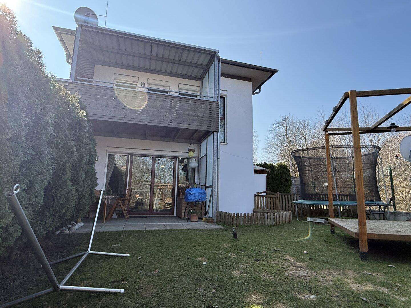 Rückansicht des Hauses mit Terrasse, Balkon und Zugang zum Garten.
