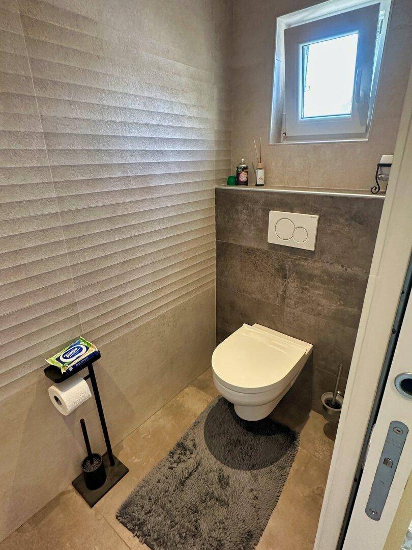 Kleines Gäste-WC mit wandhängender Toilette und einem Fenster.