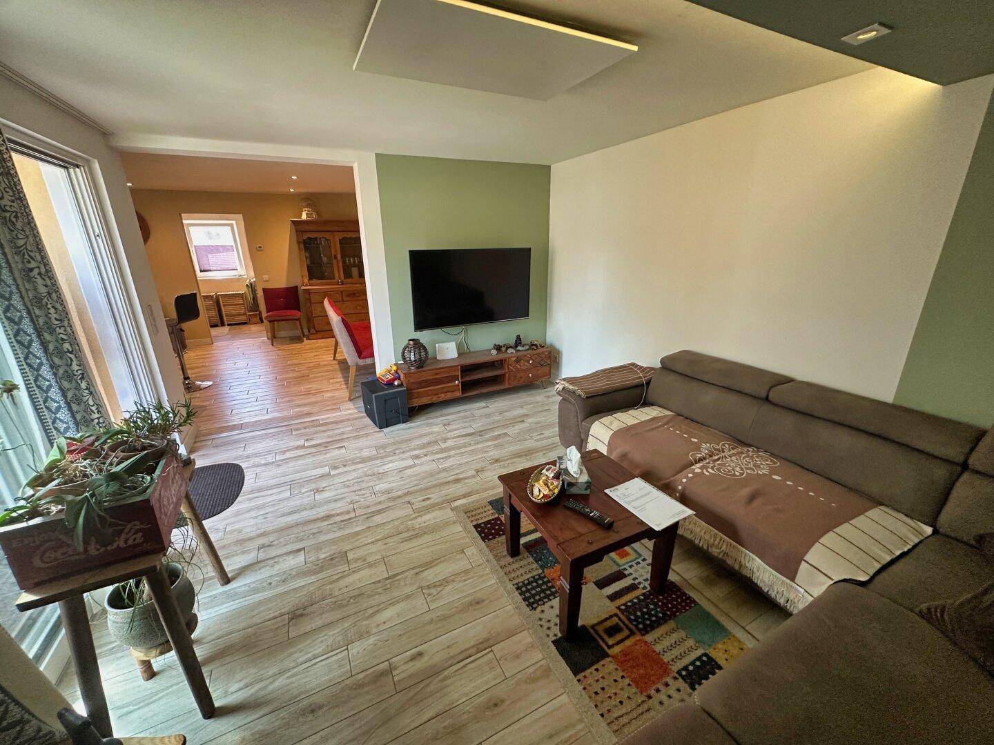 Geräumiges Wohnzimmer mit großem Sofa, Fernseher und Blick in den Essbereich.