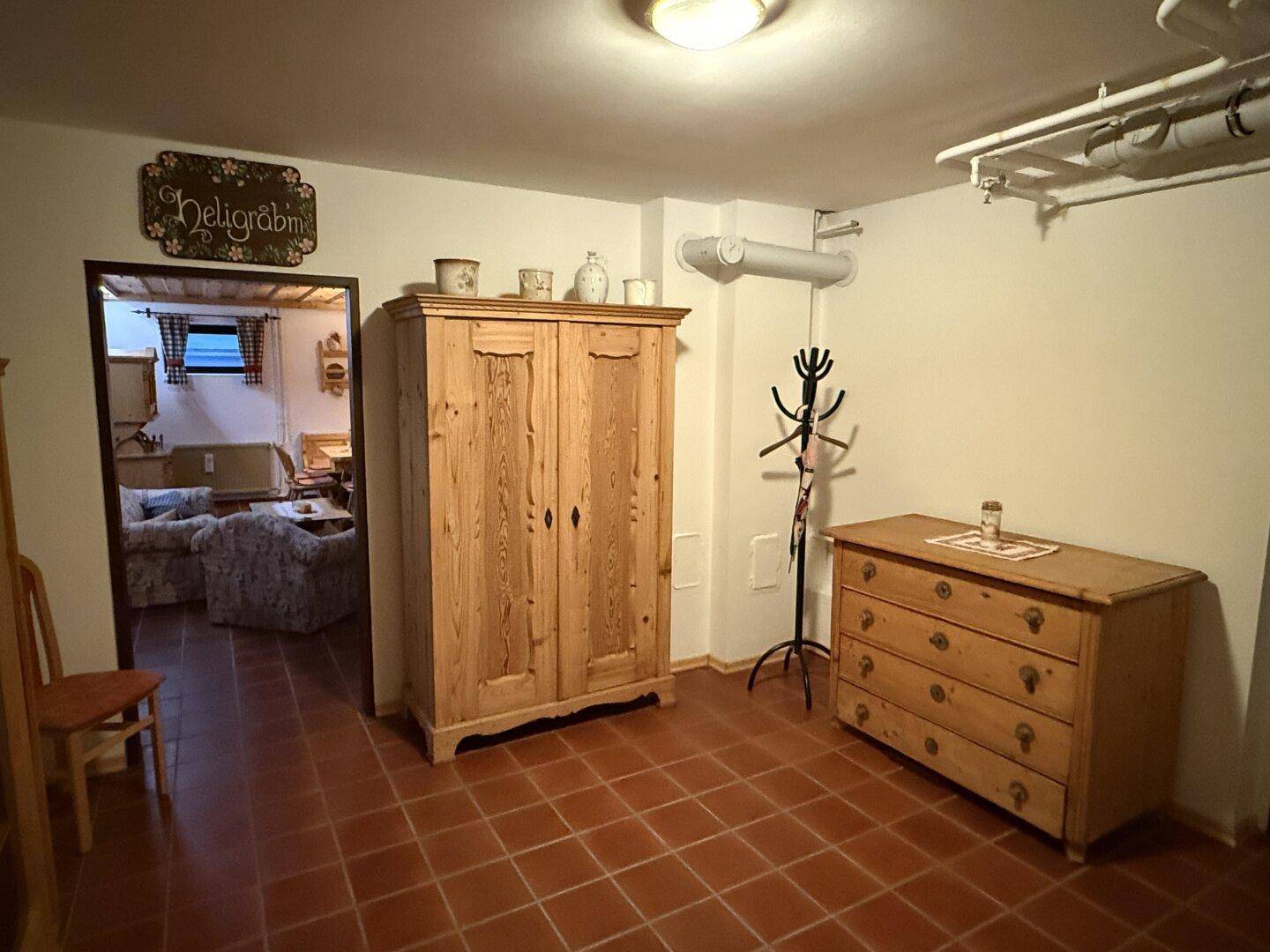 Eingangsbereich im Keller mit Fliesenboden und traditionellen Holzmöbeln.