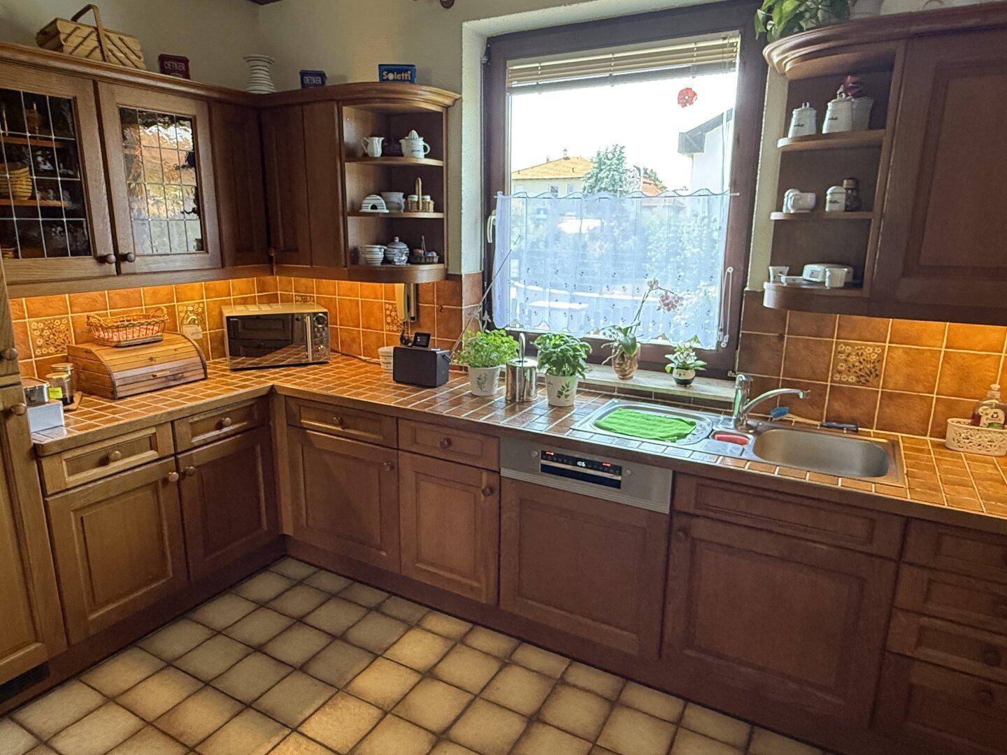 Gemütliche Holzküche mit Spülbereich, gefliester Rückwand und Fenster für natürliches Licht.