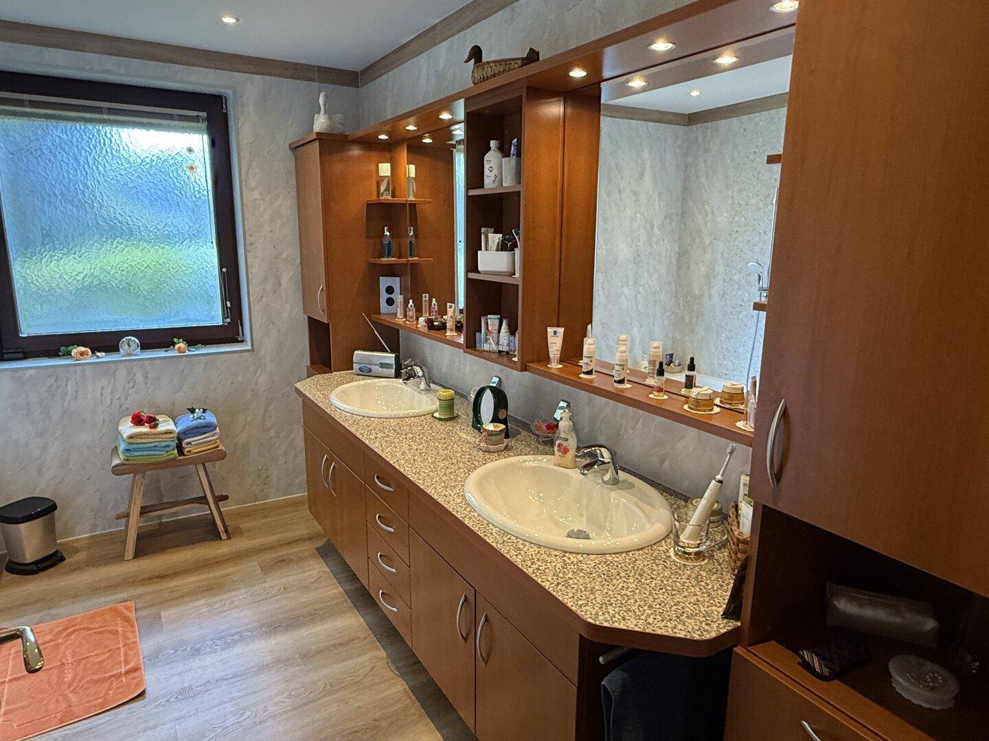 Badezimmer mit Doppelwaschbecken, großem Spiegel und Fenster für Tageslicht.