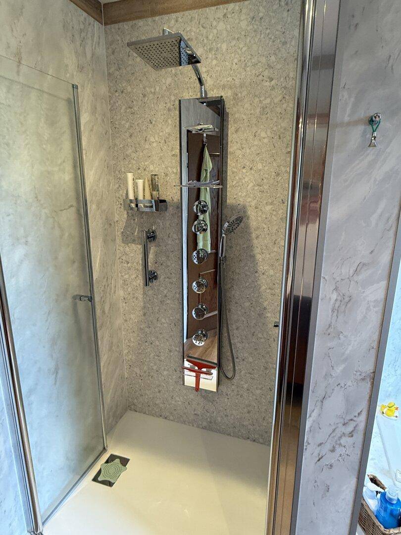 Moderne Duschkabine mit Regendusche und integriertem Duschpaneel im Badezimmer.