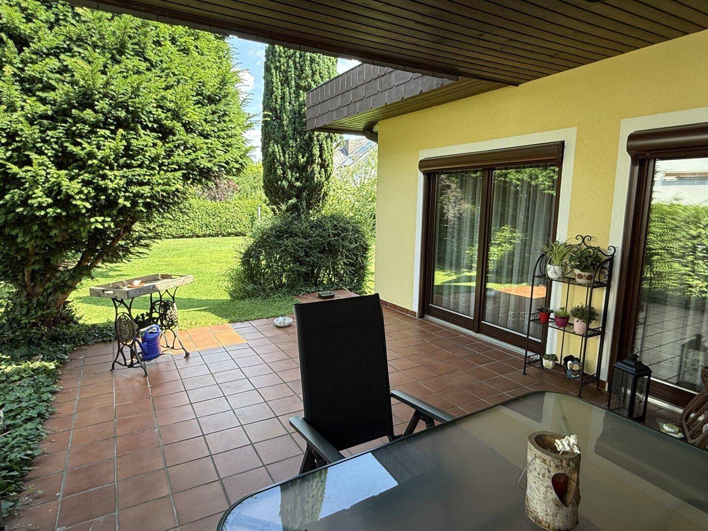 Überdachte Terrasse mit Gartenmöbeln und Blick auf den gepflegten Rasen.