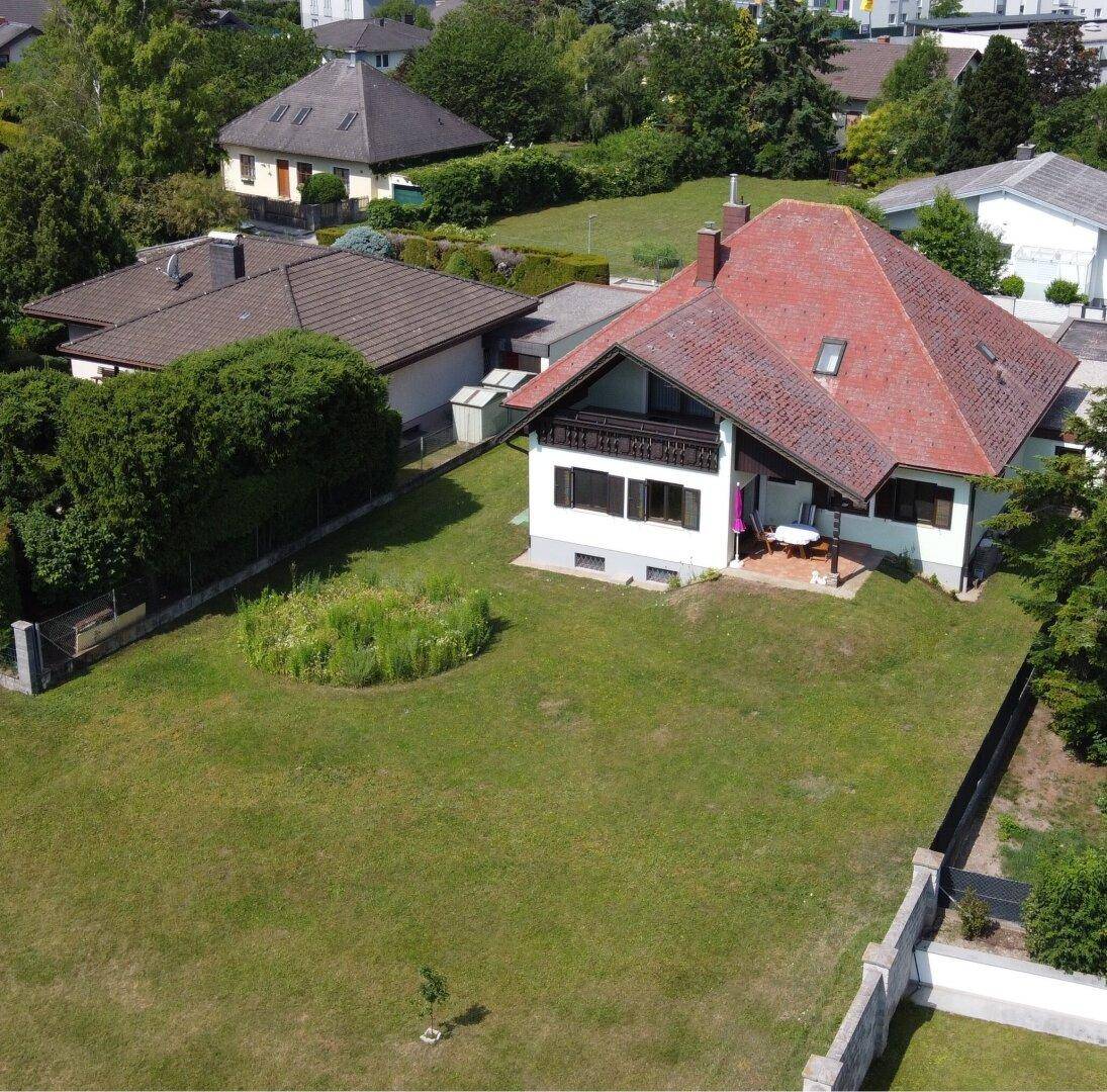 Rückansicht des Hauses mit großem, gepflegtem Rasen und angrenzender Terrasse.