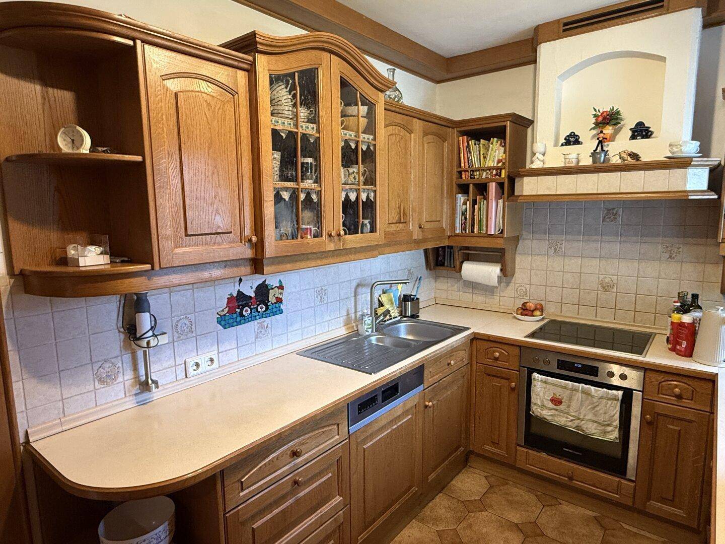 Traditionelle Holzküche mit Einbauschränken, Fliesenrückwand und integrierten Geräten.