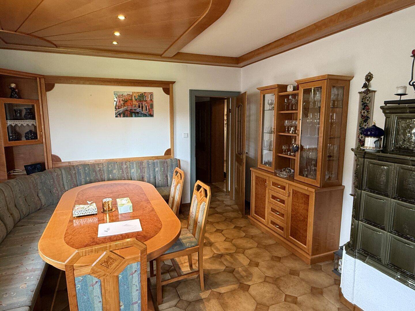 Essbereich mit traditionellem Kachelofen, Holzmöbeln und gefliestem Boden.