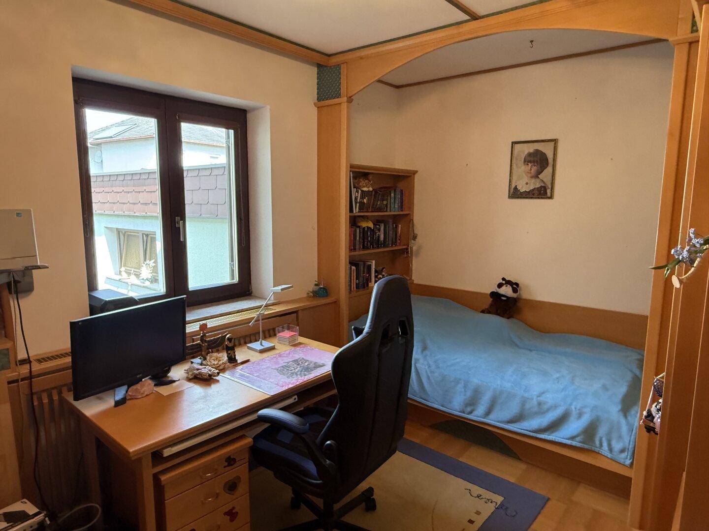 Arbeitszimmer mit Schreibtisch, Bett und Fenster mit Blick auf die Umgebung.