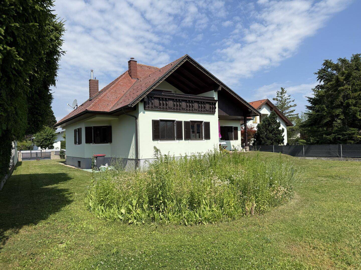 Seitenansicht des Hauses mit großem, naturbelassenem Gartenbereich und viel Grün.