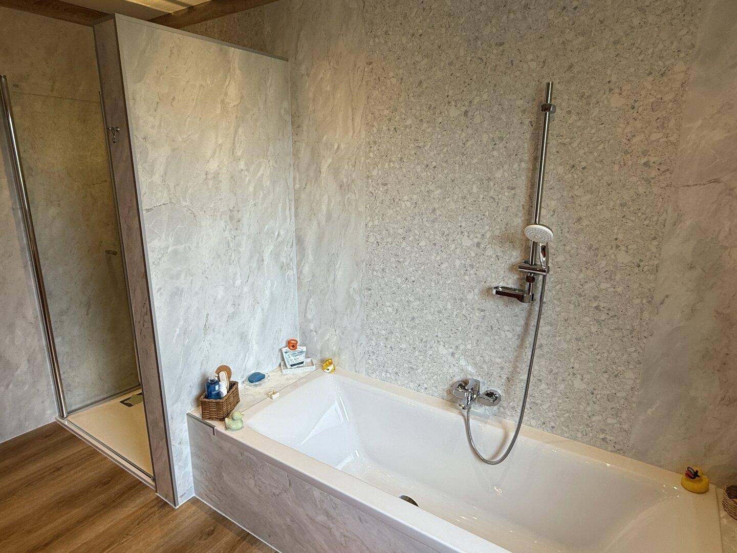 Badezimmer mit Badewanne und Duschkabine, ausgestattet mit modernen Wandpaneelen.