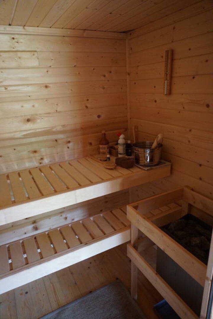 Traditionelle Holzsauna mit mehreren Bänken und Saunaofen für Entspannung.
