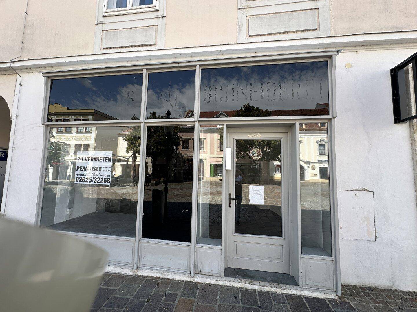 Moderne Ladenfassade mit großen Schaufenstern und einer Glastür, die den Eingang bildet.