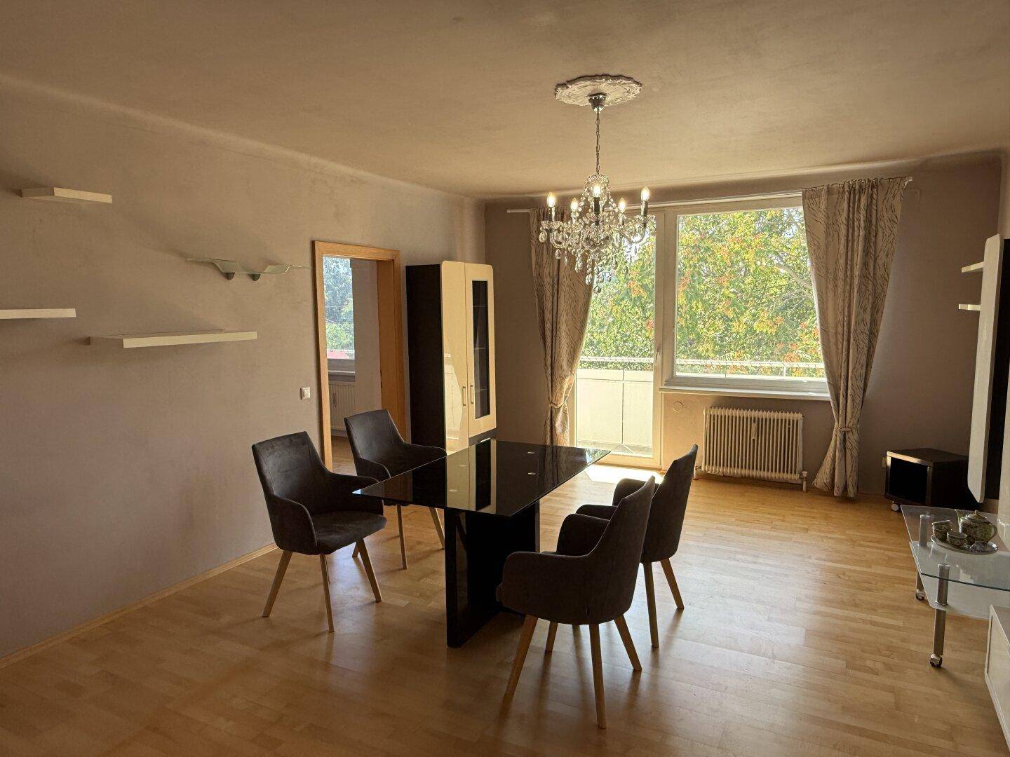 Geräumiger Wohn- und Essbereich mit großem Fenster, das viel Tageslicht und einen grünen Ausblick bietet.