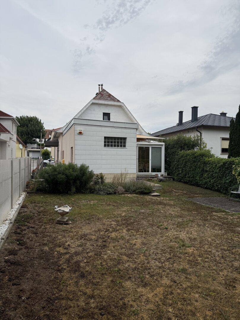 Rückseite des Hauses mit Wintergarten und Blick auf den Gartenbereich.