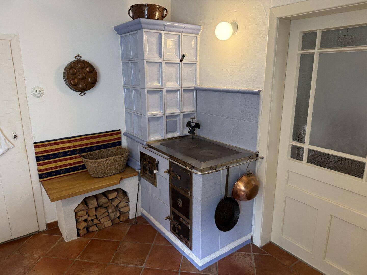 Traditioneller Kachelofen in einer Küche mit Terrakotta-Fliesen und rustikalem Charme.