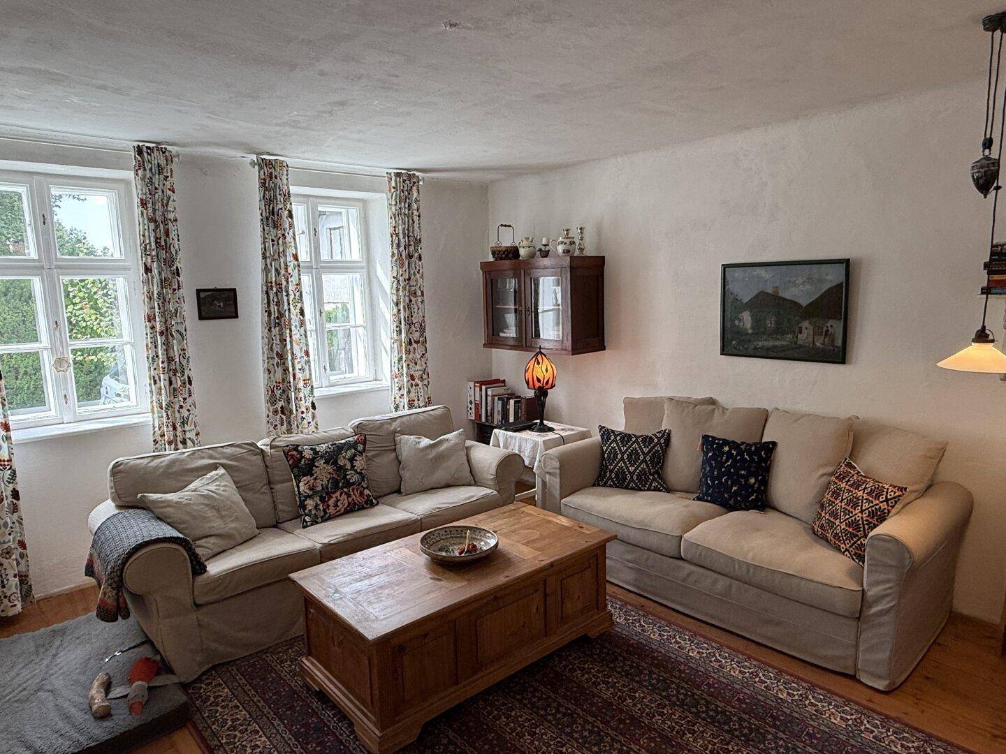 Gemütliches Wohnzimmer mit zwei Sofas, Holztisch und Teppichboden in traditionellem Ambiente.
