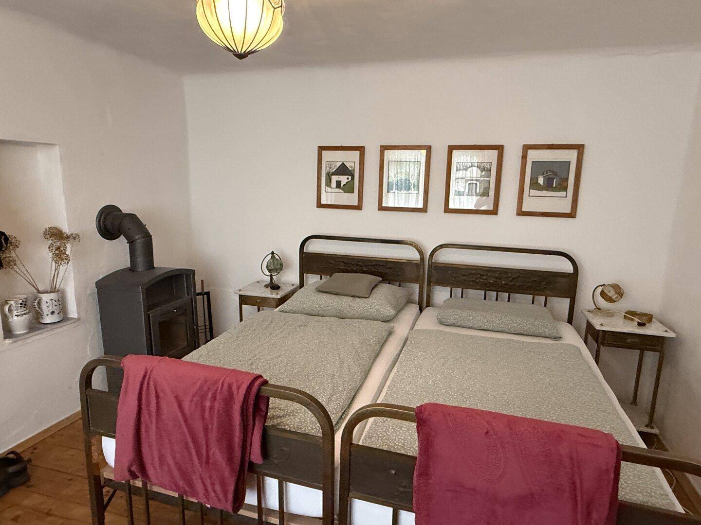 Schlafzimmer mit zwei Einzelbetten, Holzboden und einem Holzofen für zusätzliche Wärme.