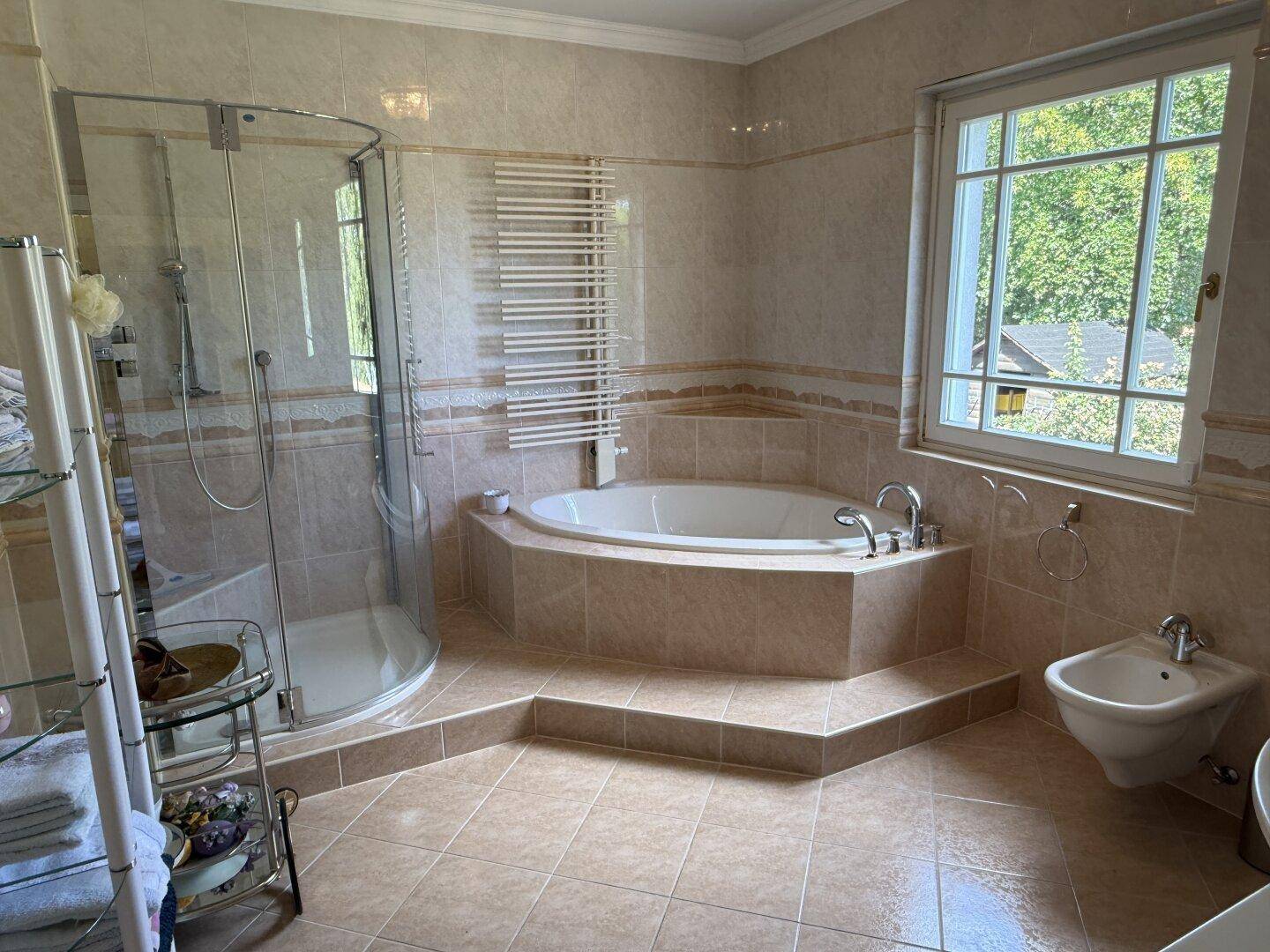 Geräumiges Badezimmer mit Eckbadewanne, Duschkabine, Bidet und Fenster.