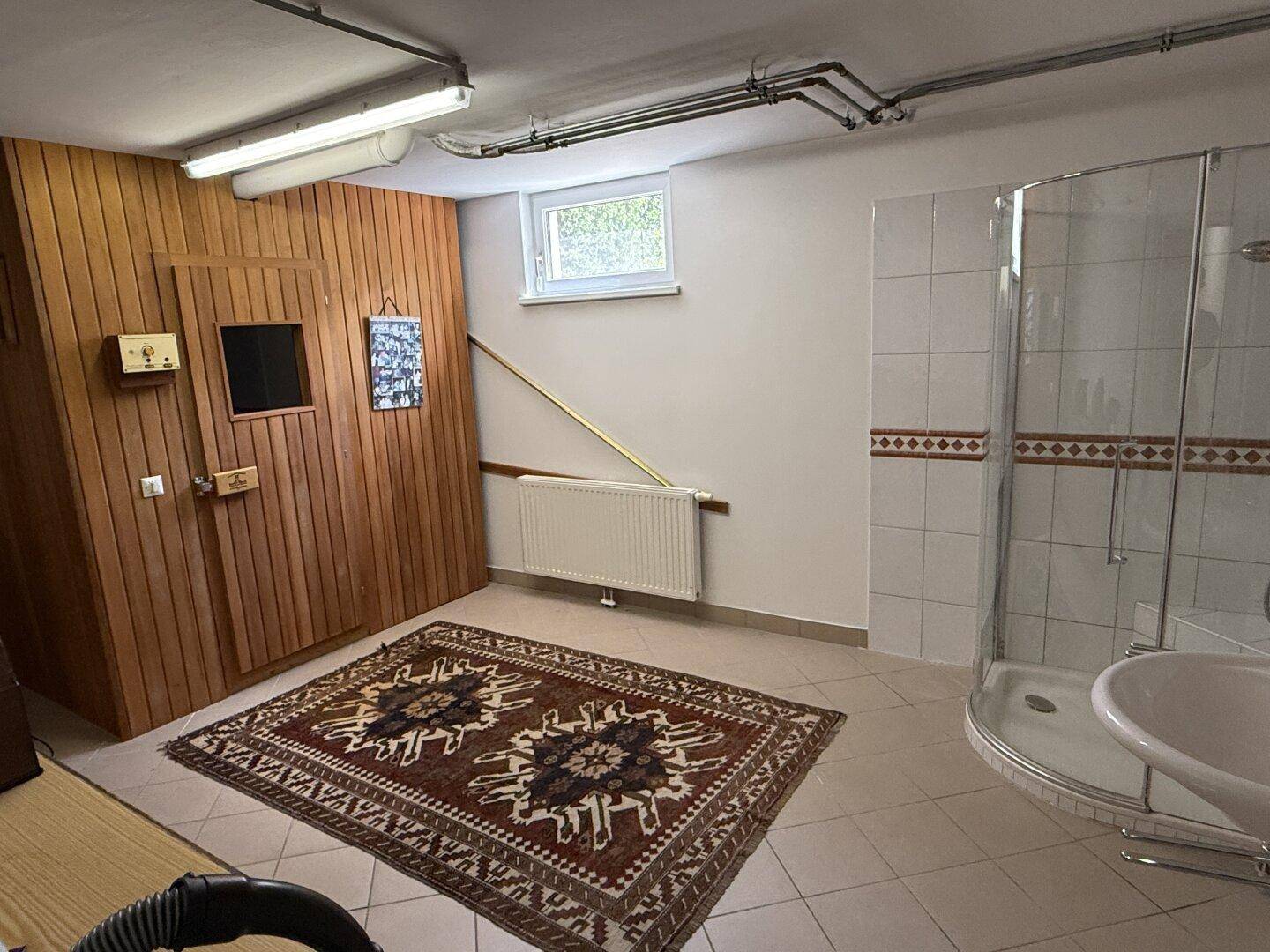 Wellnessbereich im Keller mit Sauna, Dusche und Waschbecken.