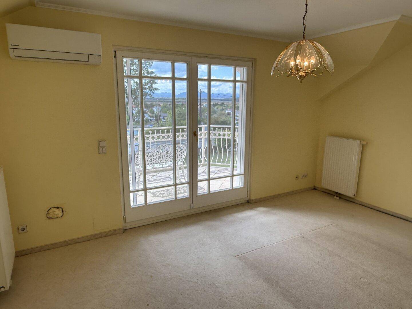 Schlafzimmer mit Teppichboden, Klimaanlage und Zugang zu einem französischen Balkon.
