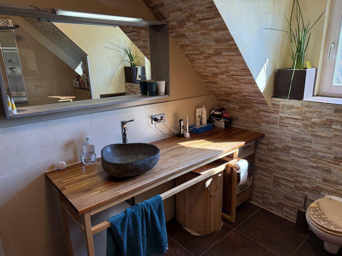 Badezimmer mit modernem Aufsatzwaschbecken auf Holzplatte und Spiegelschrank.