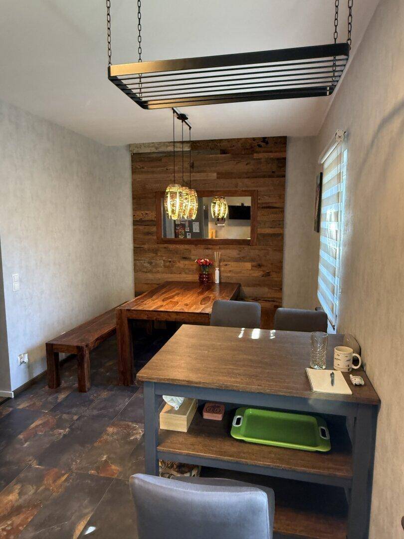 Essbereich mit Holztisch, Sitzbank und dekorativer Holzvertäfelung an der Wand.