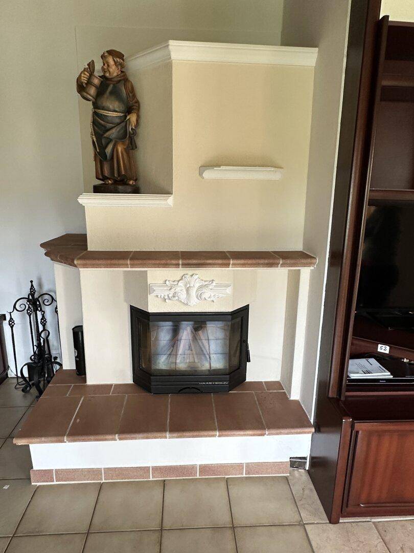 Detailansicht eines Kamins mit dekorativem Sims und einer Statue, umgeben von Fliesen.