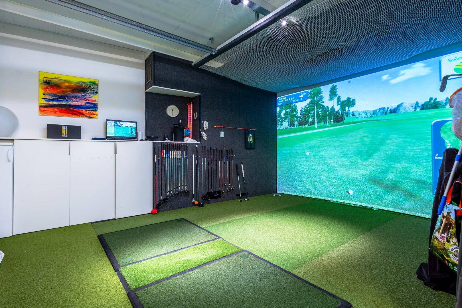 Exklusiver Indoor-Golfsimulatorraum mit Kunstrasen und Sportausrüstung.