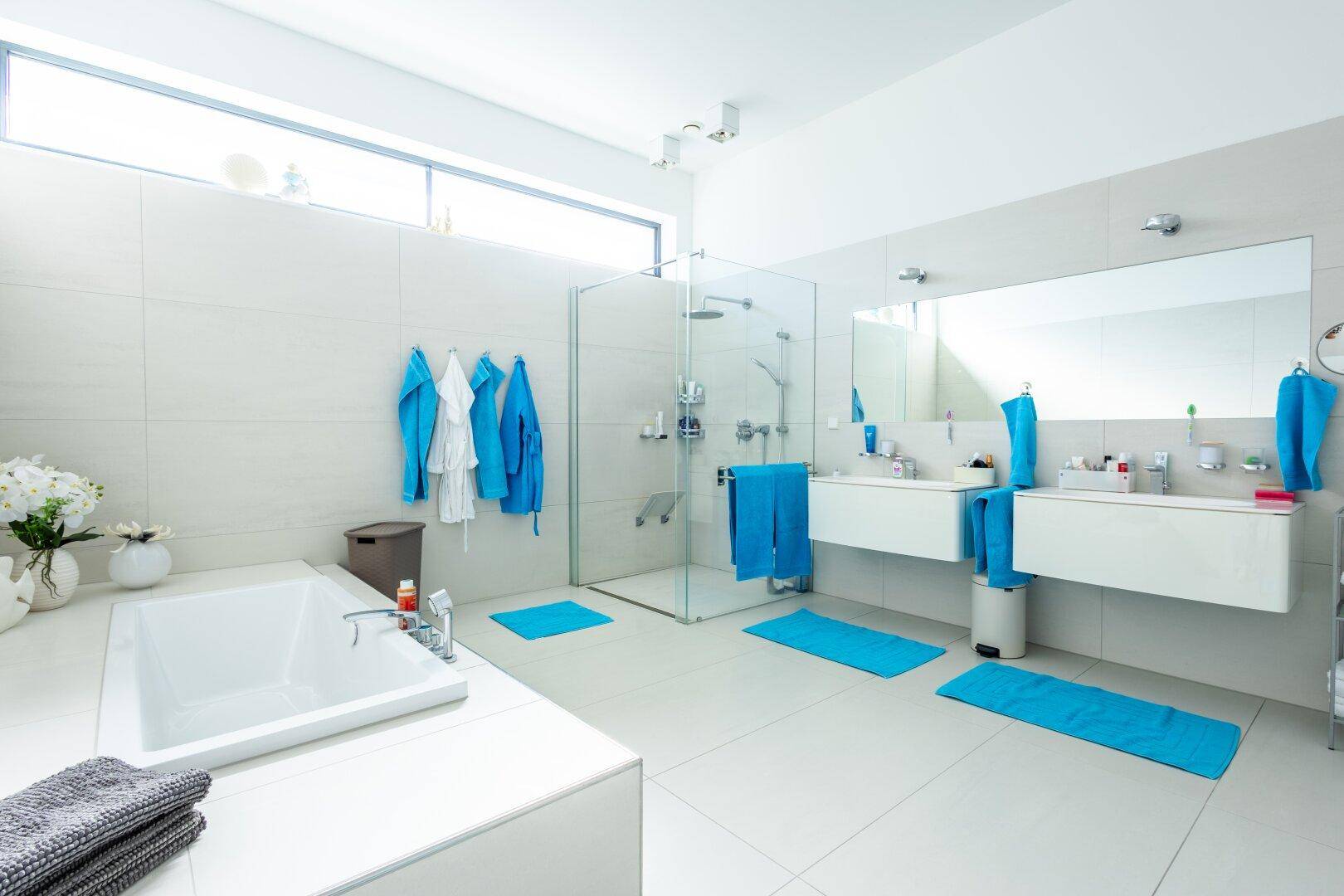 Geräumiges, helles Badezimmer mit Badewanne, Glasdusche und zwei Waschbecken.