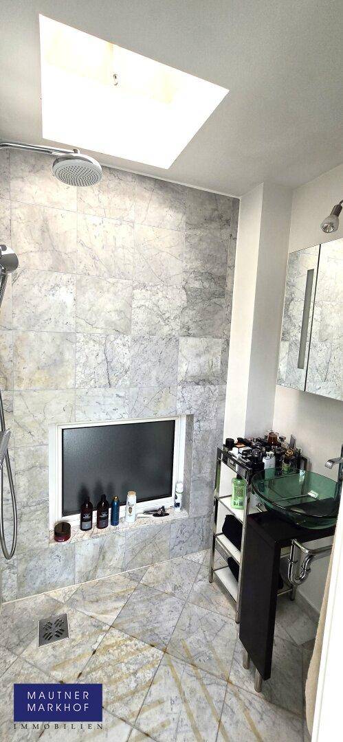 Modernes Badezimmer mit Marmorfliesen, begehbarer Dusche, Aufsatzwaschbecken und Oberlicht.