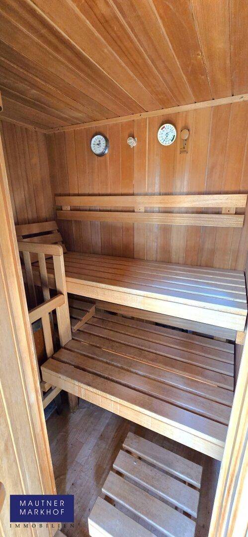 Gemütlicher Innenraum einer Holzsauna mit mehrstufigen Bänken und Temperaturanzeigen.